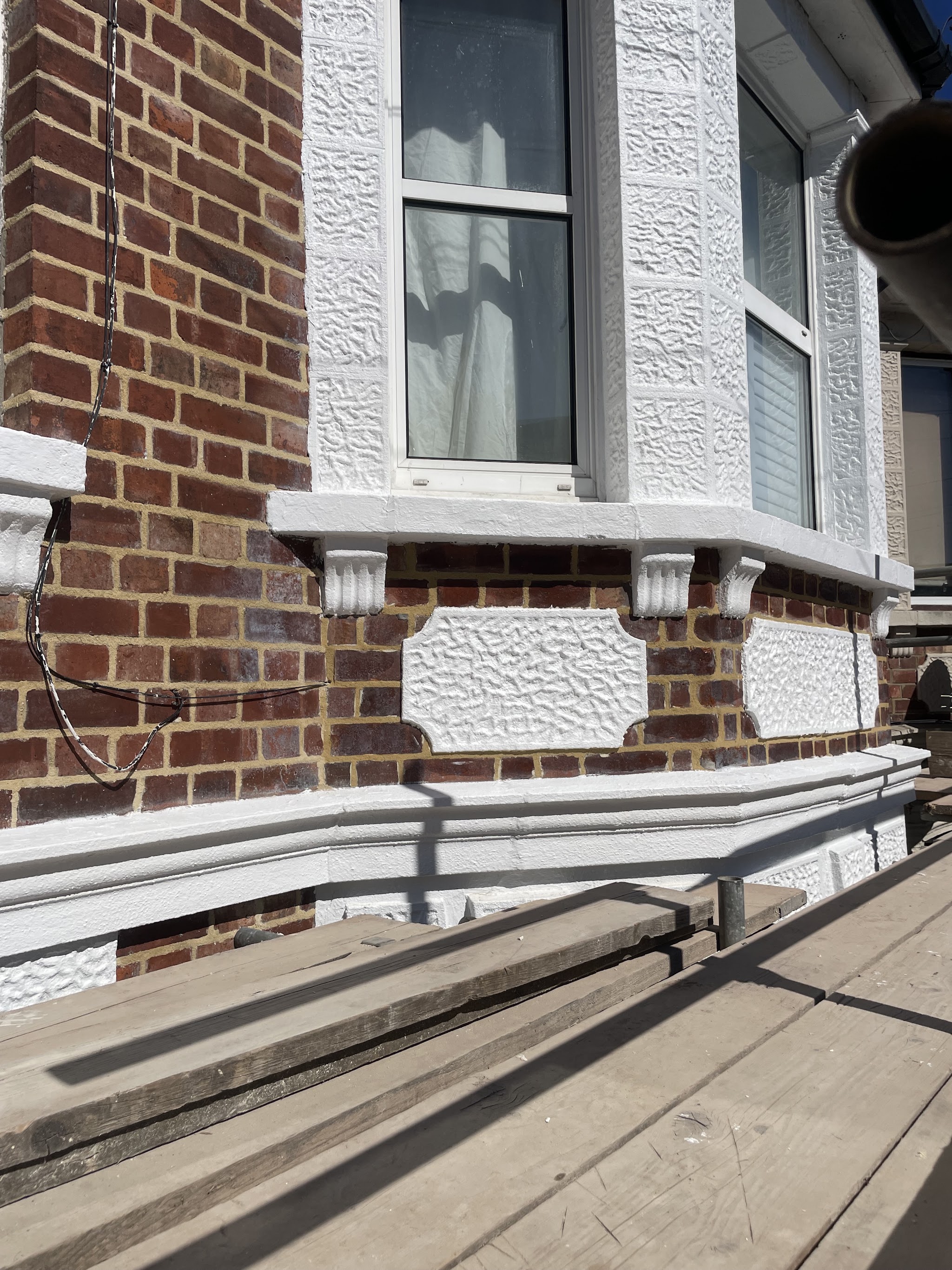 Repointed red brick beneath a Victorian bay